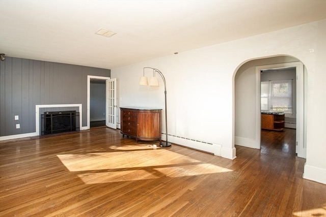 unfurnished living room featuring dark hardwood / wood-style flooring and a baseboard heating unit