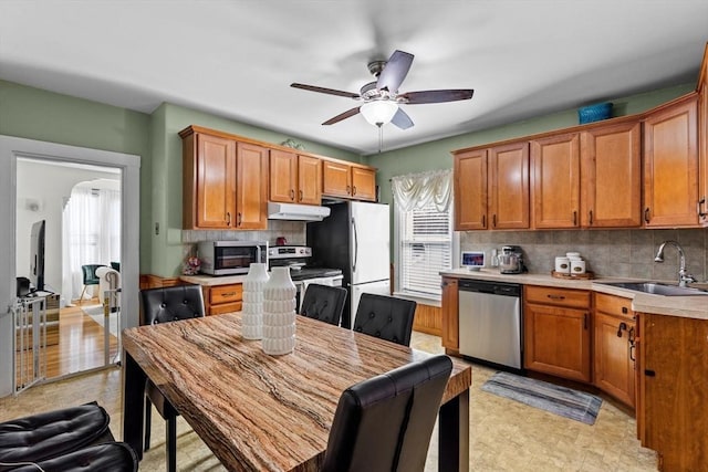 kitchen with decorative backsplash, stainless steel appliances, a sink, and light countertops