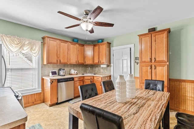 kitchen featuring dishwasher, light countertops, wainscoting, and wooden walls