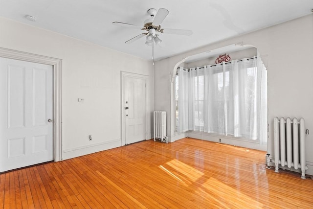 unfurnished room featuring ceiling fan, radiator heating unit, and hardwood / wood-style flooring