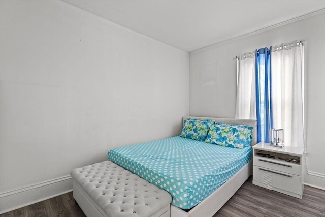 bedroom with multiple windows, wood finished floors, and baseboards