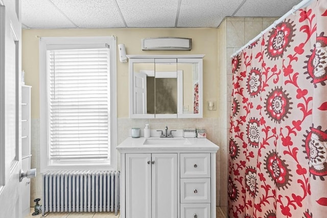 full bathroom featuring a shower with shower curtain, a drop ceiling, vanity, and radiator heating unit