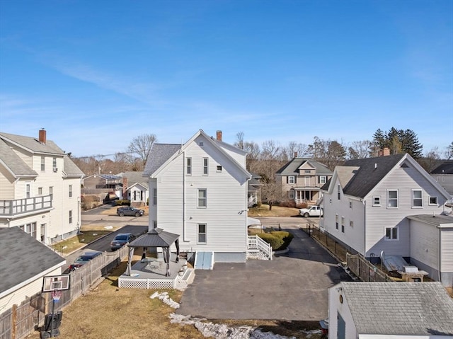 rear view of property with a gazebo, a chimney, fence, and a residential view