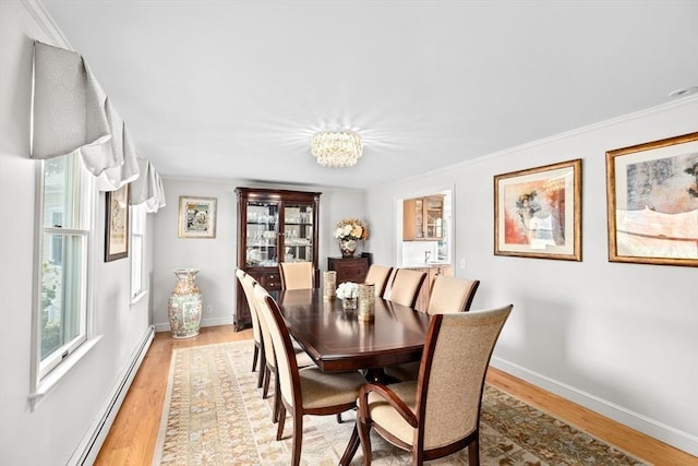 dining space with a baseboard heating unit, light wood-type flooring, an inviting chandelier, baseboards, and ornamental molding