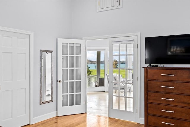 doorway featuring light wood-style floors, baseboards, and french doors