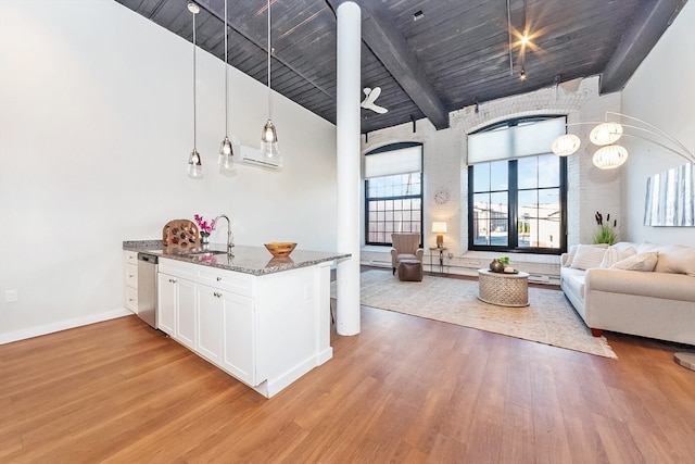 kitchen featuring sink, decorative light fixtures, dark stone countertops, light hardwood / wood-style floors, and white cabinetry