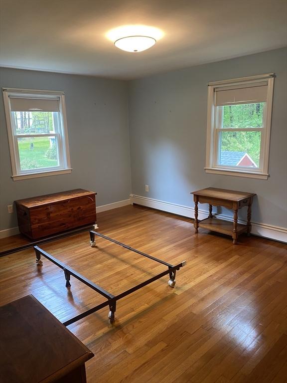 unfurnished bedroom with wood-type flooring, multiple windows, and baseboards