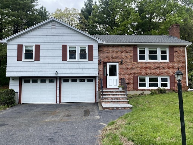 bi-level home with driveway, a chimney, an attached garage, a front yard, and roof with shingles