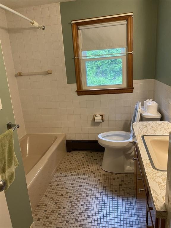 full bathroom with tile walls, toilet, vanity, a wainscoted wall, and tile patterned floors