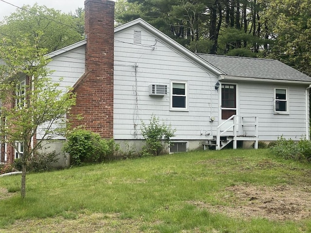 back of property featuring a lawn, a chimney, roof with shingles, and an AC wall unit