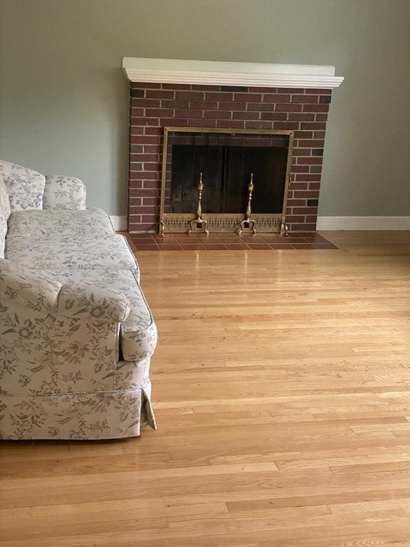 bedroom / living area view of a tile fireplace, wood finished floors, and baseboards