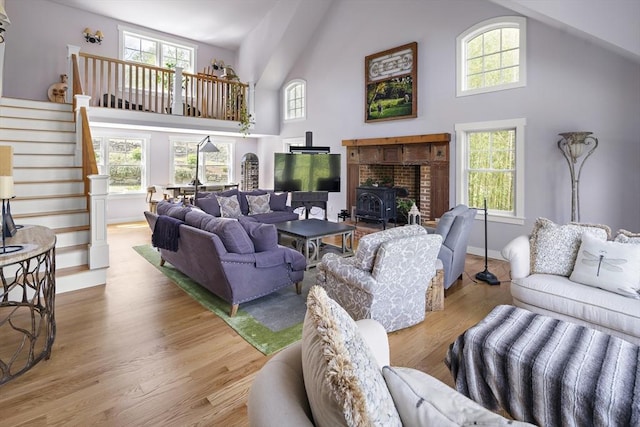 living room with a towering ceiling, light wood-type flooring, and a wood stove