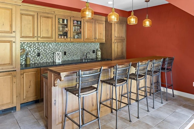 bar featuring sink, hanging light fixtures, light tile patterned flooring, and backsplash