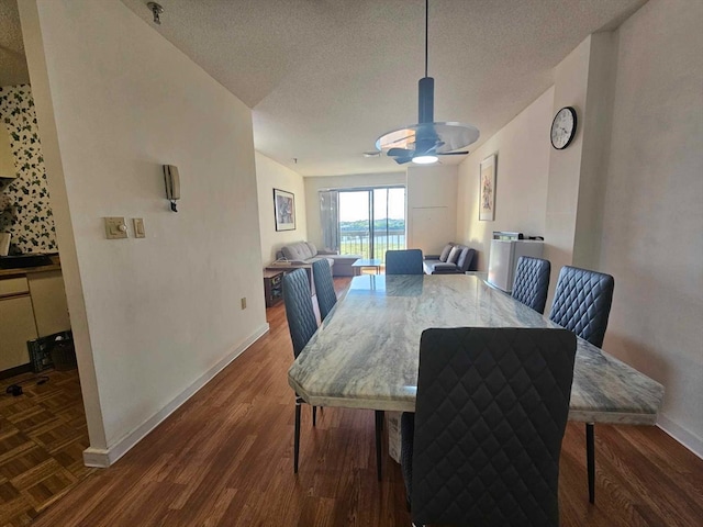 dining space featuring dark wood-type flooring and a textured ceiling