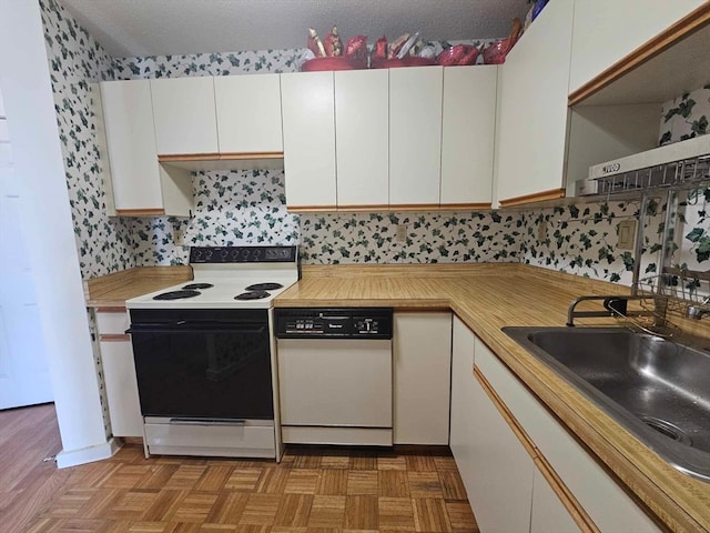 kitchen featuring white appliances, backsplash, sink, light parquet floors, and white cabinets