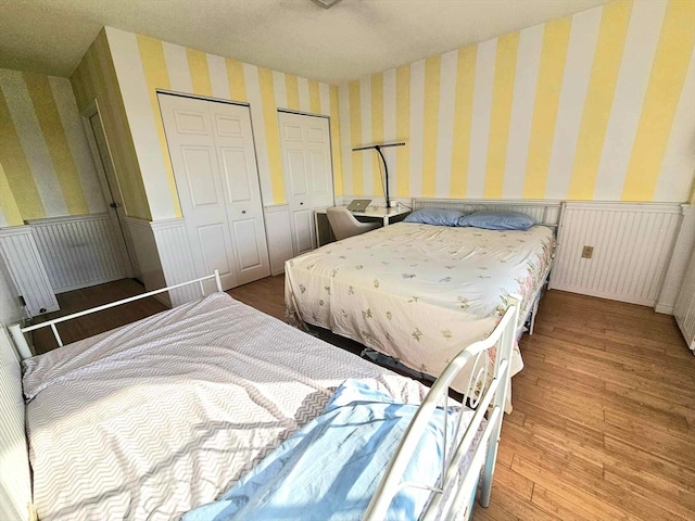 bedroom with light hardwood / wood-style flooring and multiple closets