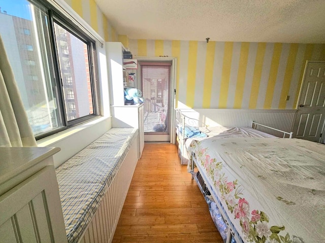 bedroom featuring a textured ceiling, light wood-type flooring, and multiple windows