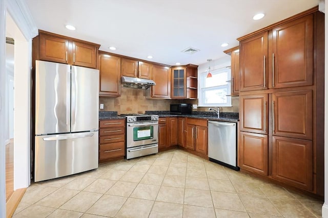 kitchen featuring sink, dark stone countertops, hanging light fixtures, backsplash, and stainless steel appliances