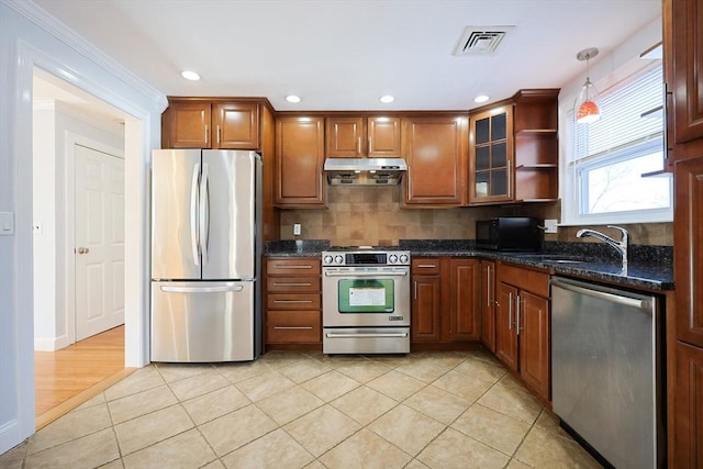 kitchen with sink, dark stone countertops, hanging light fixtures, light tile patterned floors, and stainless steel appliances