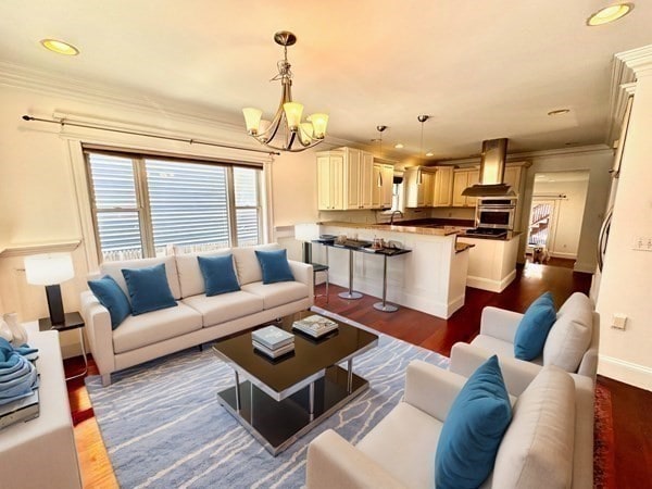 living room featuring dark hardwood / wood-style flooring, a notable chandelier, and crown molding