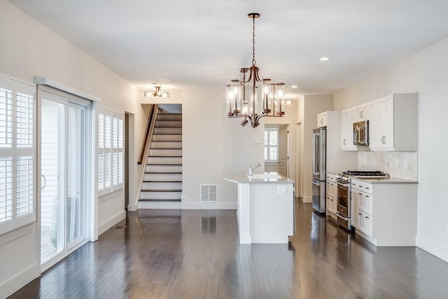 kitchen with high end appliances, tasteful backsplash, visible vents, dark wood-type flooring, and a sink