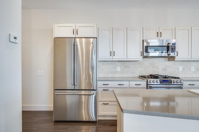 kitchen featuring dark wood-style flooring, white cabinetry, baseboards, appliances with stainless steel finishes, and decorative backsplash