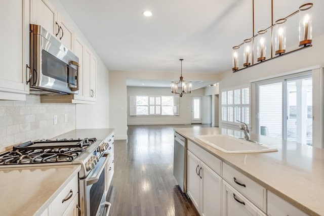 kitchen with dark wood-type flooring, a sink, white cabinetry, appliances with stainless steel finishes, and backsplash