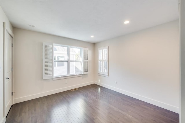 spare room featuring dark wood-style floors, recessed lighting, visible vents, and baseboards