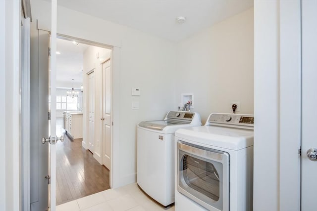 clothes washing area with laundry area, washing machine and dryer, and light tile patterned floors