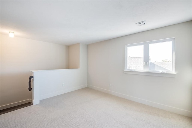 empty room with carpet, visible vents, and baseboards