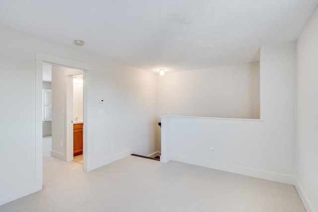 unfurnished room featuring light carpet and baseboards