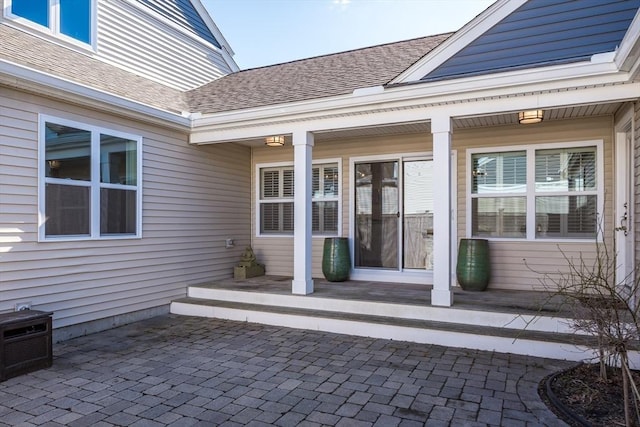 entrance to property with a patio and roof with shingles