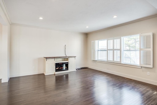 unfurnished living room with dark wood-style flooring, visible vents, ornamental molding, a glass covered fireplace, and baseboards