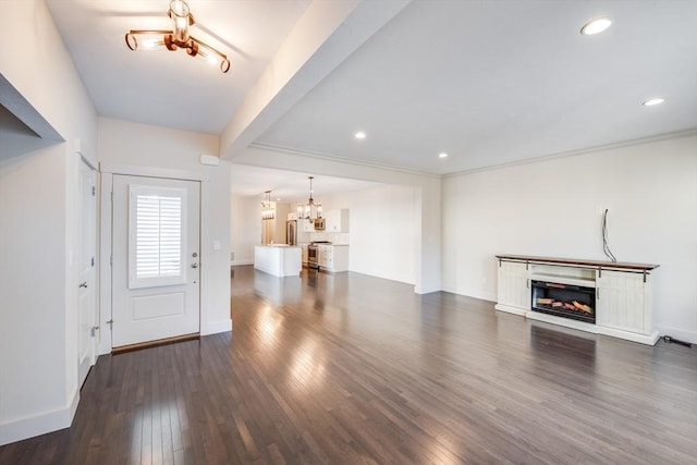 unfurnished living room with a notable chandelier, a fireplace, dark wood-type flooring, and recessed lighting