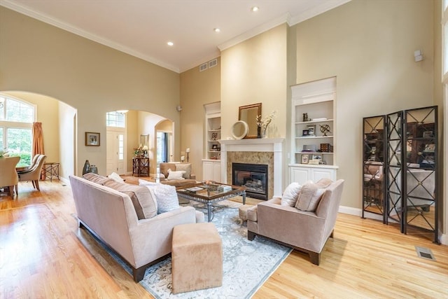 7 Brimfield Way, Westfield, MA 01085 - living room with arched walkways, a towering ceiling, light wood-type flooring, built in features, and a tiled fireplace