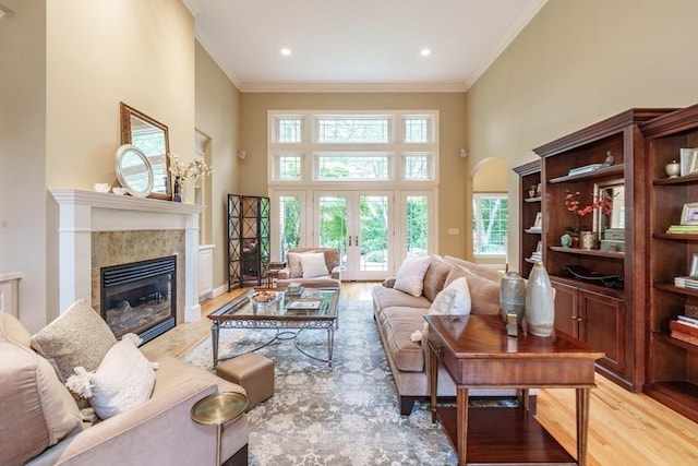 7 Brimfield Way, Westfield, MA 01085 - living room with light wood-style flooring, a towering ceiling, crown molding, a tile fireplace, and french doors