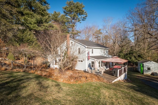 back of property featuring a gazebo, a shed, a yard, and a deck