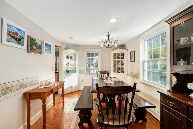 dining area with a wealth of natural light, a chandelier, and hardwood / wood-style flooring