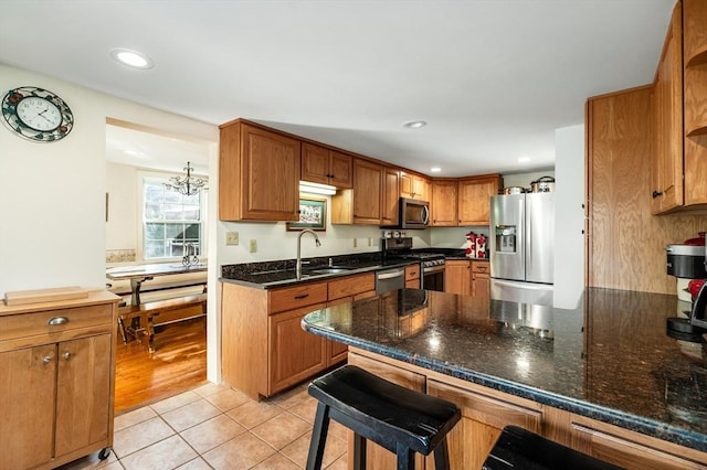 kitchen with sink, light tile patterned floors, a notable chandelier, a kitchen bar, and stainless steel appliances