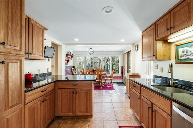 kitchen with kitchen peninsula, stainless steel dishwasher, sink, light tile patterned floors, and dark stone countertops