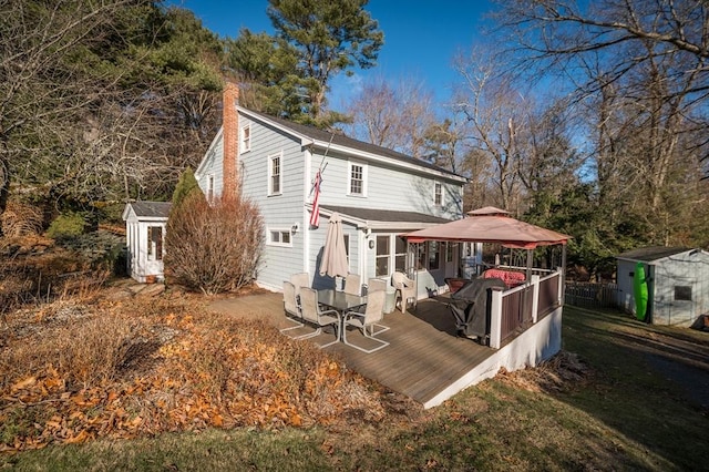 rear view of house with a gazebo, a storage unit, a patio area, and a lawn