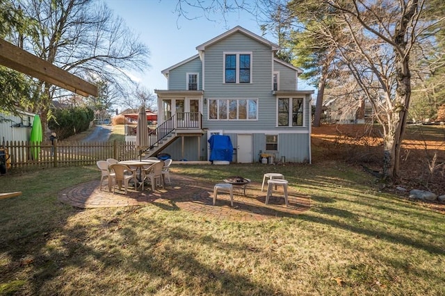 back of house featuring a fire pit, a patio, and a lawn