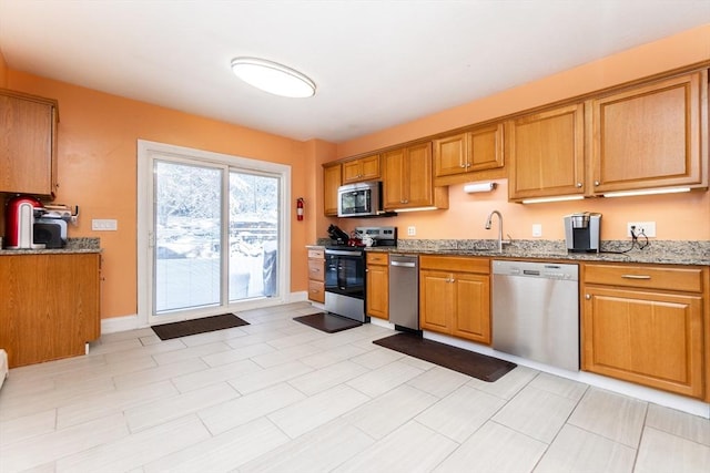 kitchen with light stone countertops, sink, and stainless steel appliances