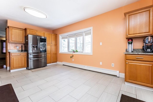 kitchen featuring light stone countertops, a baseboard radiator, and stainless steel fridge