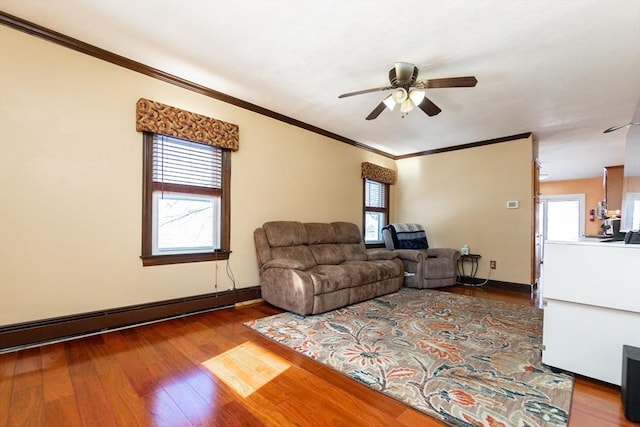 living room featuring ceiling fan, wood-type flooring, a baseboard heating unit, and ornamental molding