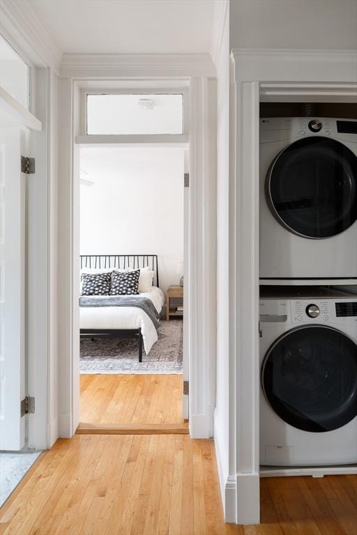 laundry area with stacked washer / drying machine, hardwood / wood-style floors, laundry area, and ornamental molding