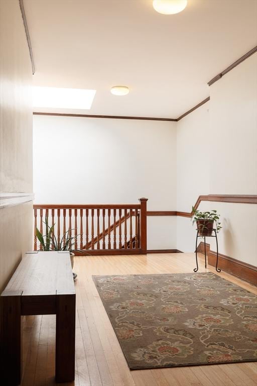 corridor with hardwood / wood-style floors, crown molding, and a skylight