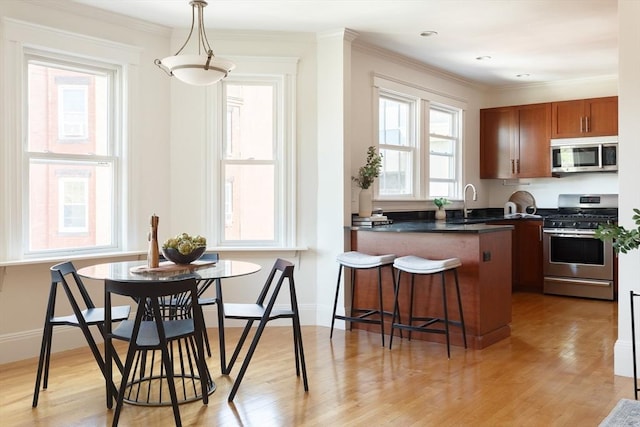 kitchen with stainless steel appliances, crown molding, dark countertops, a kitchen breakfast bar, and brown cabinets