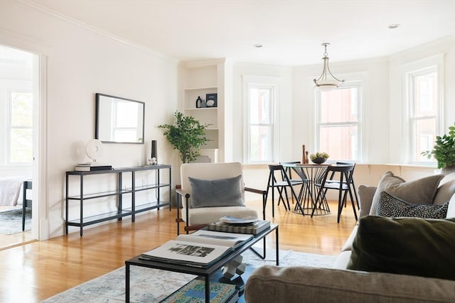 living area featuring ornamental molding, built in shelves, and wood finished floors