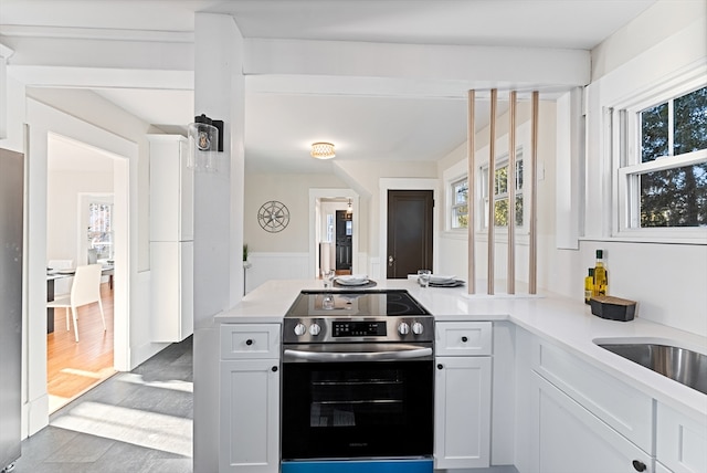 kitchen with electric stove, white cabinetry, and kitchen peninsula